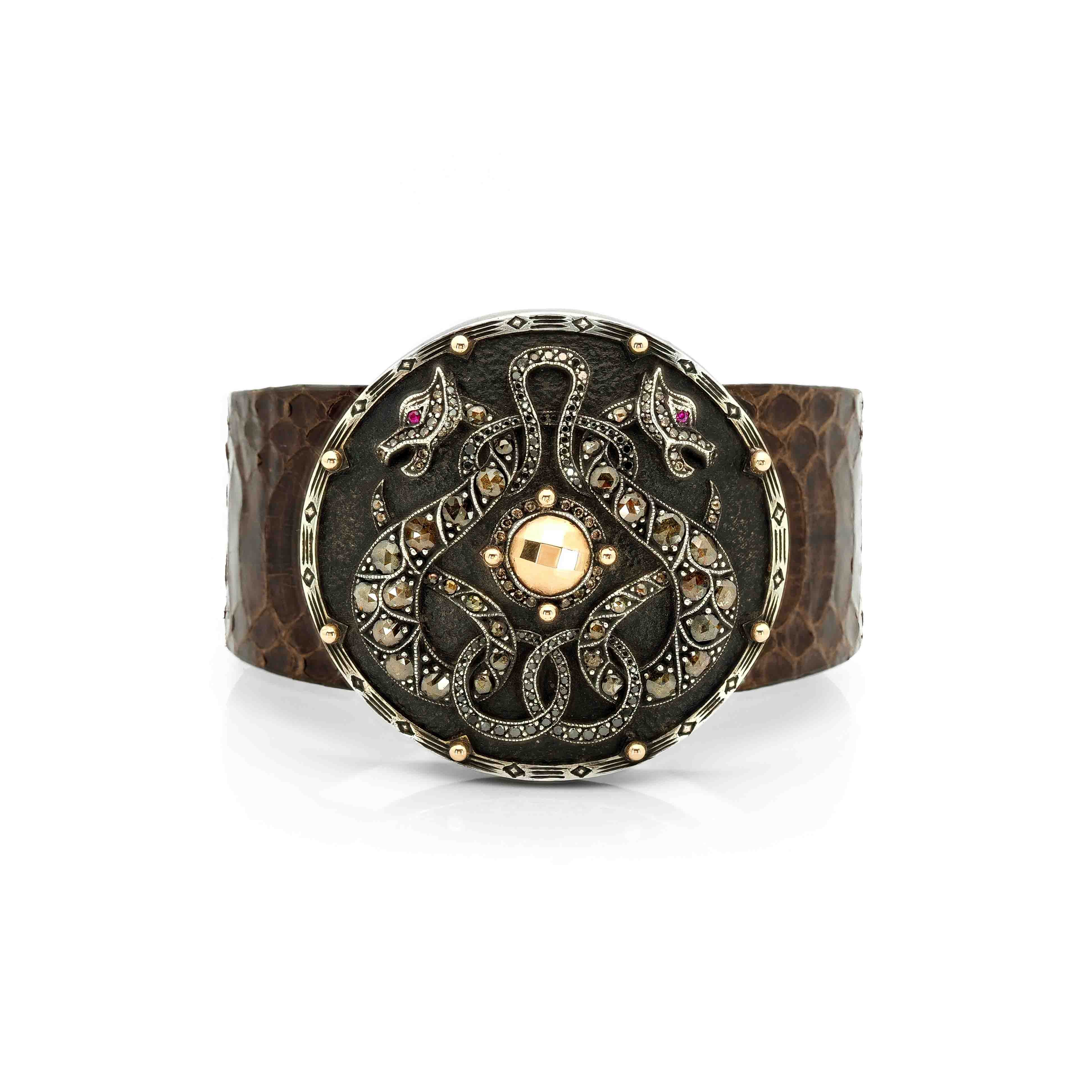 Taru Jewelry Dragon Shield Bracelet is a bold piece crafted from 18K gold and sterling silver. Featuring a majestic design of two dragons, it is adorned with brown rosecut diamonds and black diamonds.