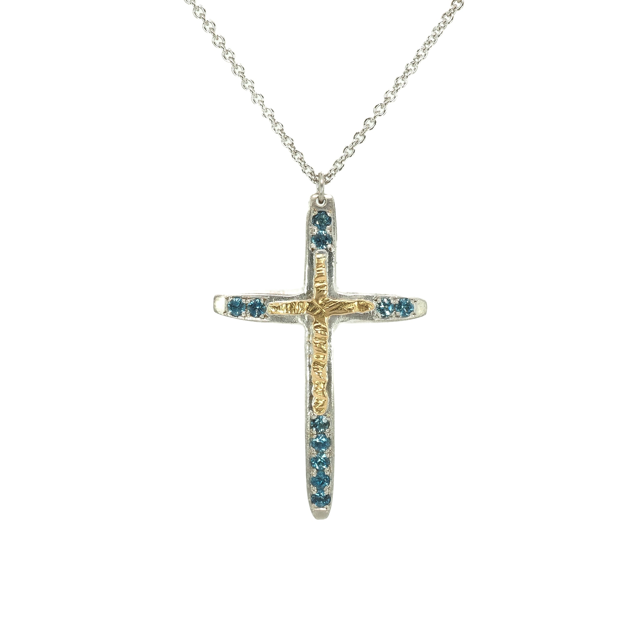 Taru Jewelry Cross Necklace made of 18K yellow gold and sterling silver is a beautiful combination of traditional symbolism and modern design. The cross, a timeless symbol of faith and devotion, is adorned with sparkling blue topaz, adding a touch of color and elegance to the piece.