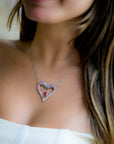 Taru Jewelry Flamingo Heart Necklace in 18K rose gold and sterling silver is a unique piece of jewelry. The design features two flamingos forming a heart shape, encrusted with pink and white sapphires and black diamonds.