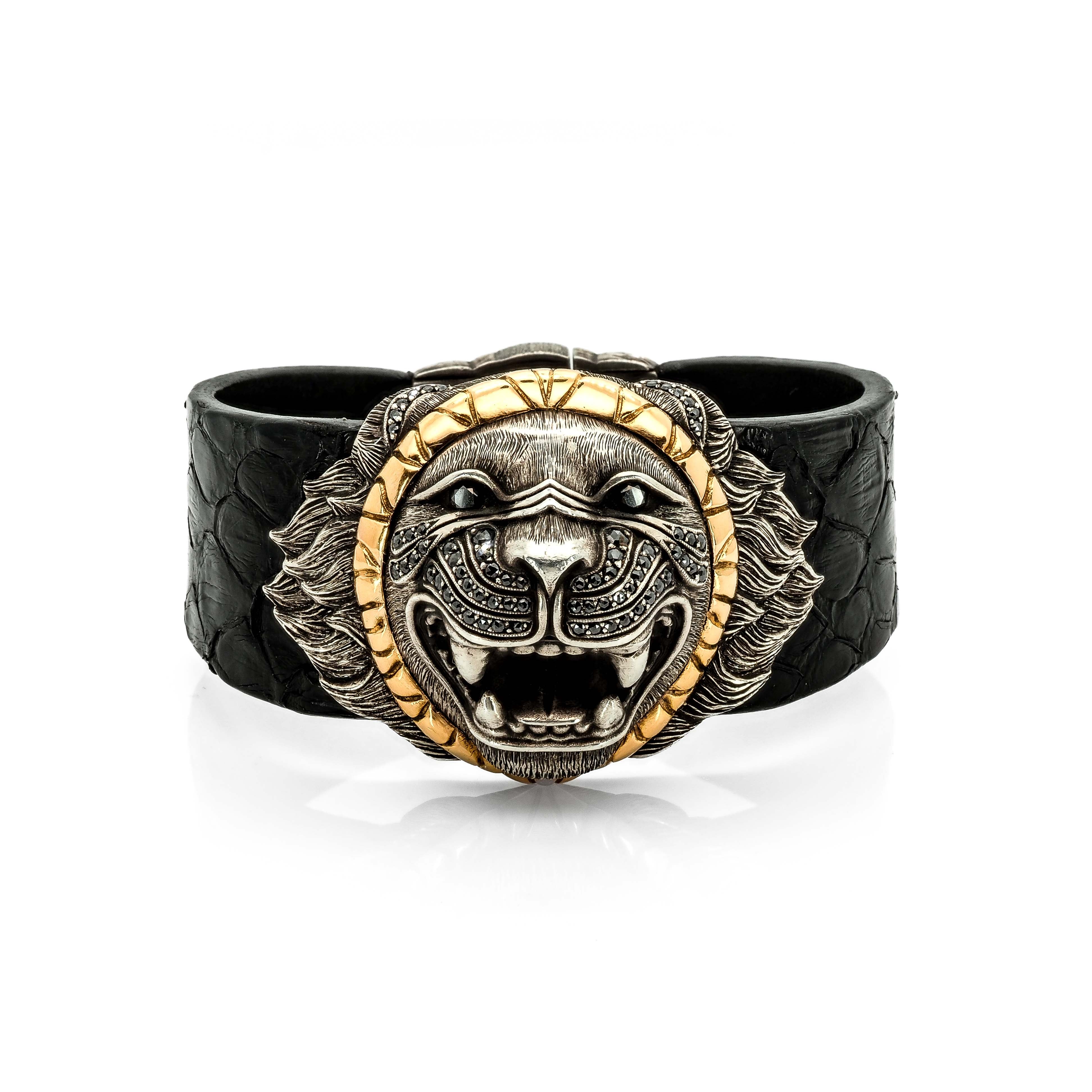Taru Jewelry luxurious lion bracelet is crafted from 18K gold, sterling silver, and features black diamonds. The lion&#39;s face is hand-engraved to capture the intricate details of its fur, and the mane is further accentuated in the clasp with colorful natural diamonds. The bracelet is finished with a black snake leather band, adding a touch of elegance to the piece.