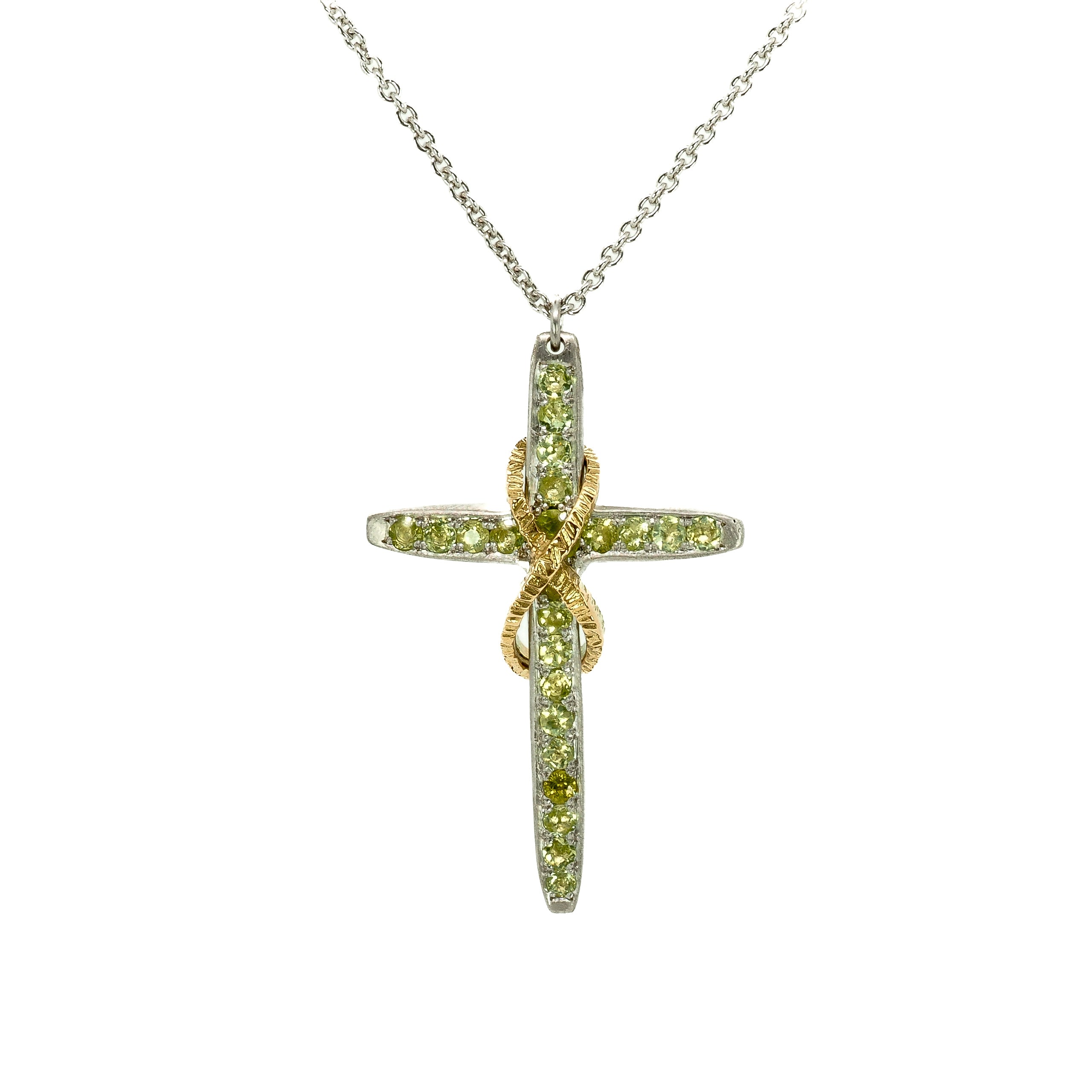 Taru Jewelry Cross and Infinity Necklace crafted from 18K yellow gold and silver is a beautiful combination of traditional symbolism and modern design. The cross, a timeless symbol of faith and devotion, is adorned with sparkling green peridot, adding a touch of color and elegance to the piece.