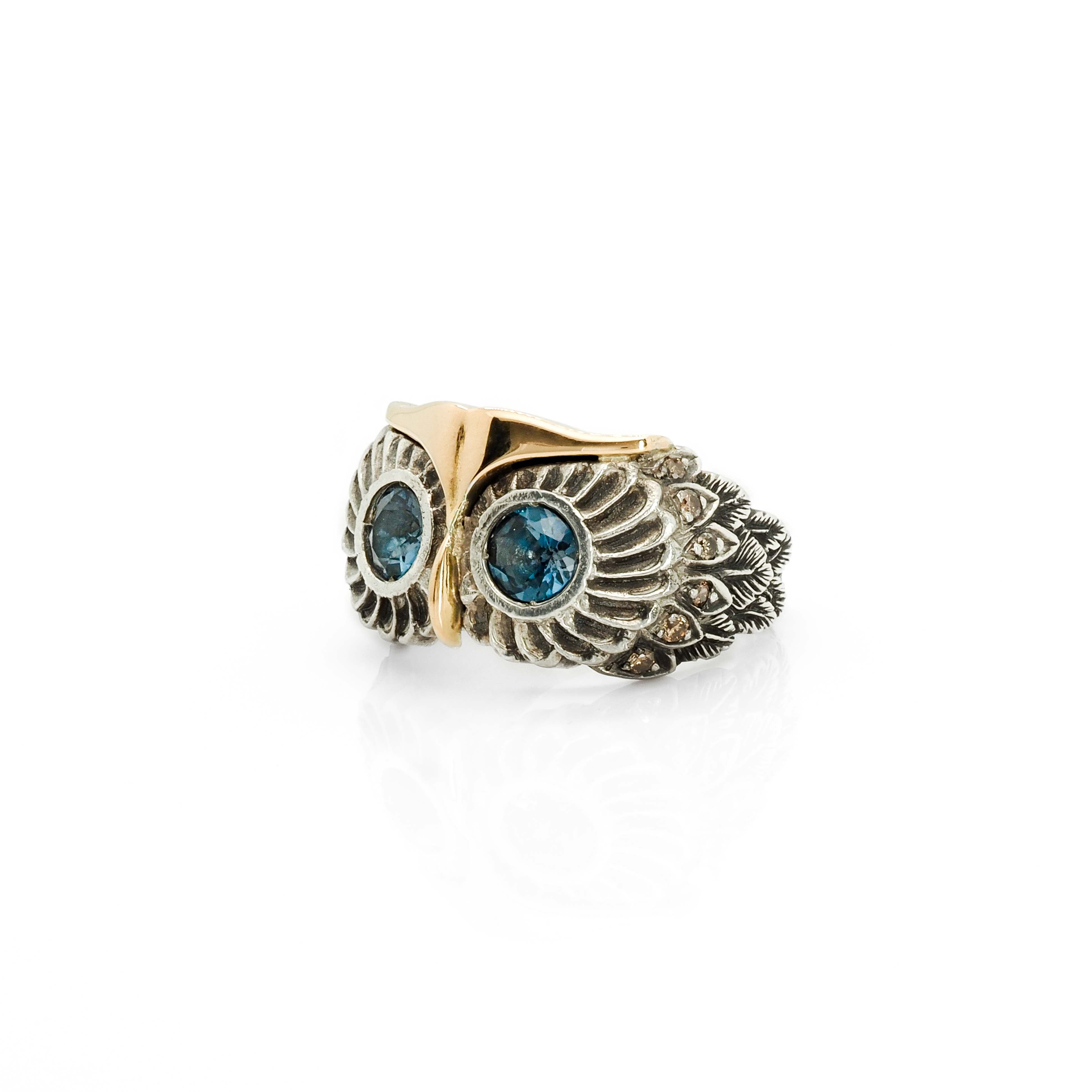 Taru Jewelry charming owl ring is a unique piece crafted from 18K gold and sterling silver, featuring a design that captures the essence of the wise and mysterious bird. The owl is a symbol of wisdom, known for its sharp vision and hearing. It is also believed to be a protector and messenger of secrets. The ring features London blue topaz as the owl&#39;s eyes, which represents loyalty and righteousness, and brown diamonds for the feathers. It is said to help improve communication and finding success.