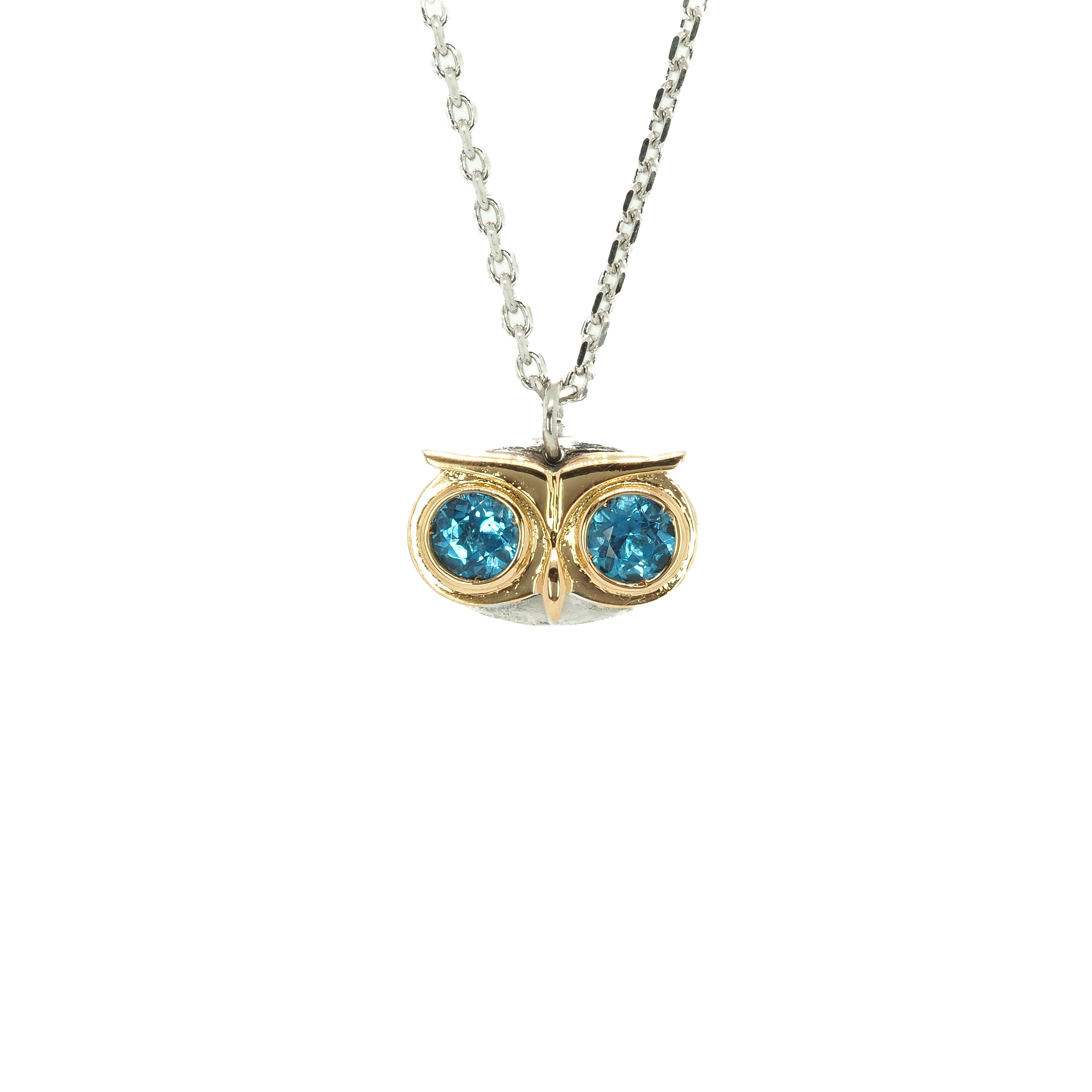 Taru Jewelry captivating owl necklace, crafted from 18K gold and sterling silver, captures the essence of the wise and mysterious bird. The owl's eyes are set with sparkling blue topaz, adding a touch of color and elegance to the piece. The blue topaz represents loyalty, righteousness, and the ability to improve communication and find the perfect pathways to success.