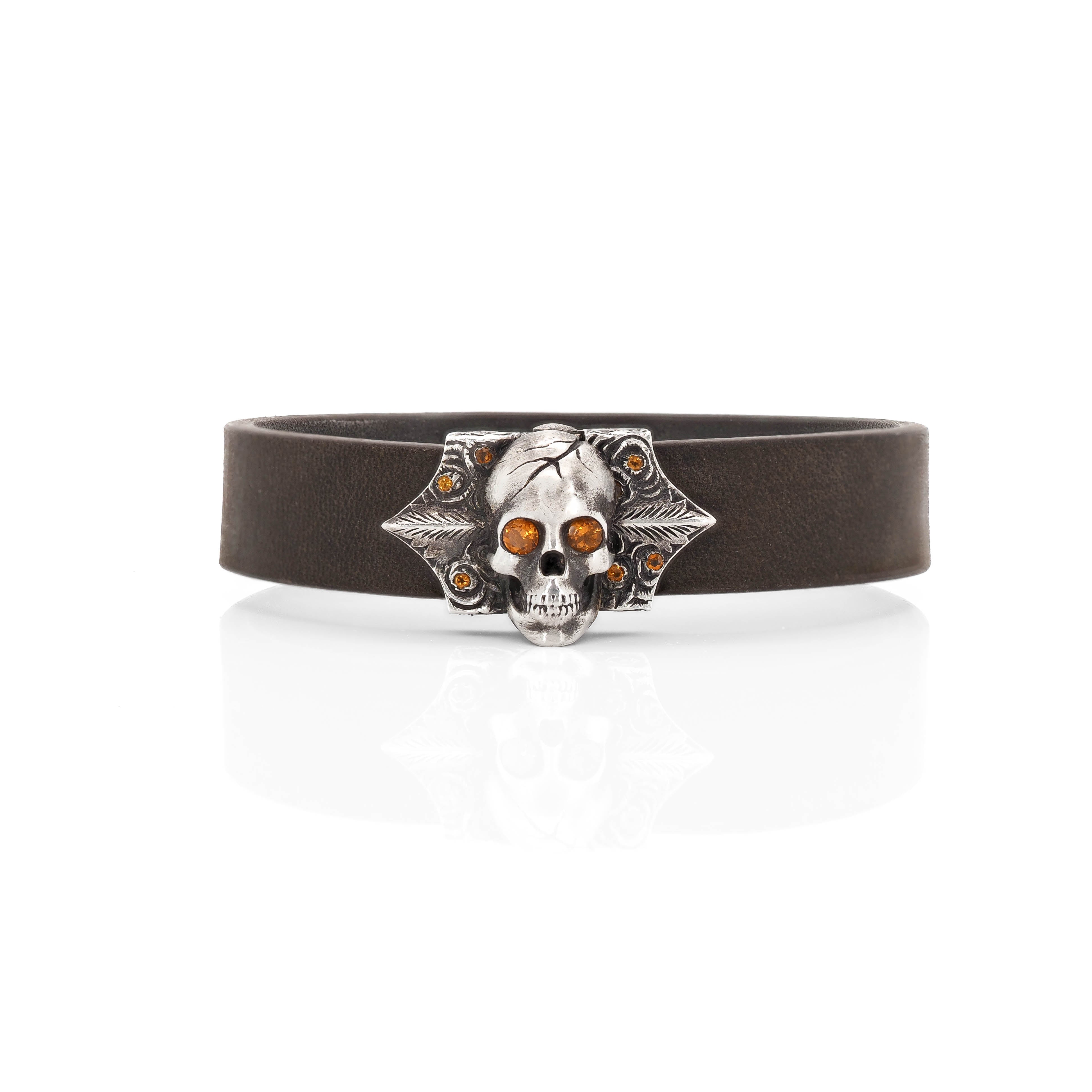 Make a bold fashion statement with Taru Jewelry Skull and Roses bracelet. Decorated with delicate rose engravings, it features glittering citrine roses and shining eyes on the skull design, making it a truly unique piece. The bracelet is strapped by a dark brown leather strap, making it both stylish and comfortable to wear.