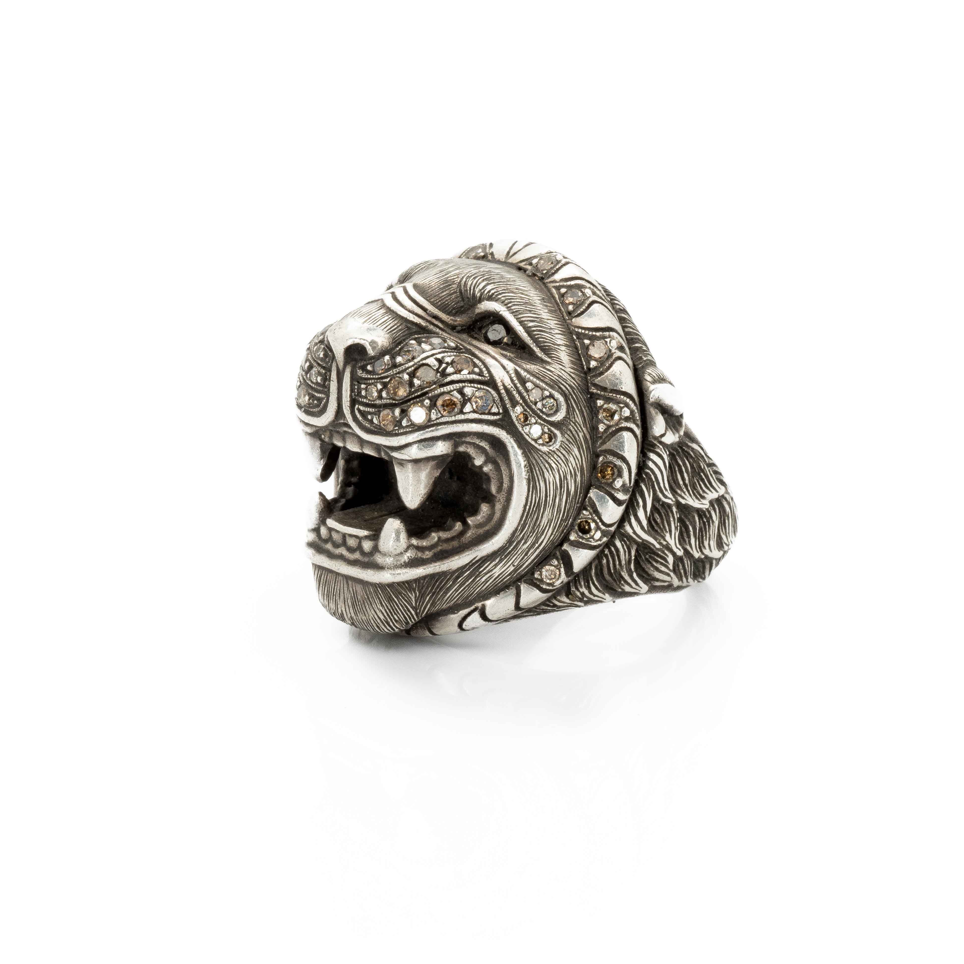 Taru Jewelry stunning lion ring is crafted from sterling silver and adorned with sparkling brown and black diamonds. The intricate details of the lion&#39;s face are hand-engraved, capturing the texture of its fur and the fierce expression of its eyes.